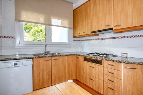 Cuina moderna amb mobles de fusta, taulell de granit, fogons de gas i finestra a Finques Garcia Enrich, Palafrugell