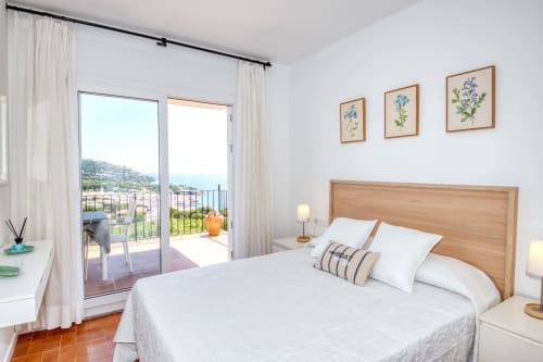 Dormitori lluminós a Finques Garcia Enrich a Palafrugell amb llit de fusta, vistes costaners i balcó amb vista al Mediterrani