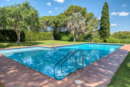Piscina del resort Finques Garcia Enrich a Palafrugell amb gandules, jardins exuberants i palmeres