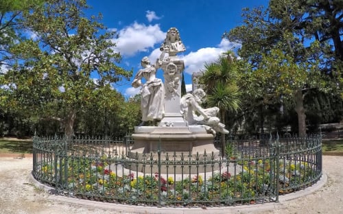 Monument en marbre blanc orné entouré de fleurs colorées et de clôture en fer forgé à La Villa Monarque, Cap d'Agde