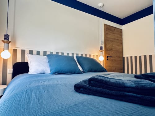 Chambre moderne à Vivre l'Instant Amboise avec literie bleue, tête de lit rayée et plafond bleu marine