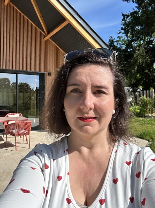 Directrice de l'hôtel Vivre l'Instant à Amboise, debout sur une terrasse avec architecture contemporaine et jardin en arrière-plan