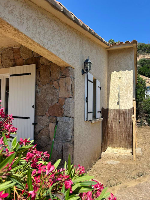 Extérieur de la chambre L'Alba à Vista D'oro, Monacia d'Aullène, avec fleurs roses et architecture en pierre