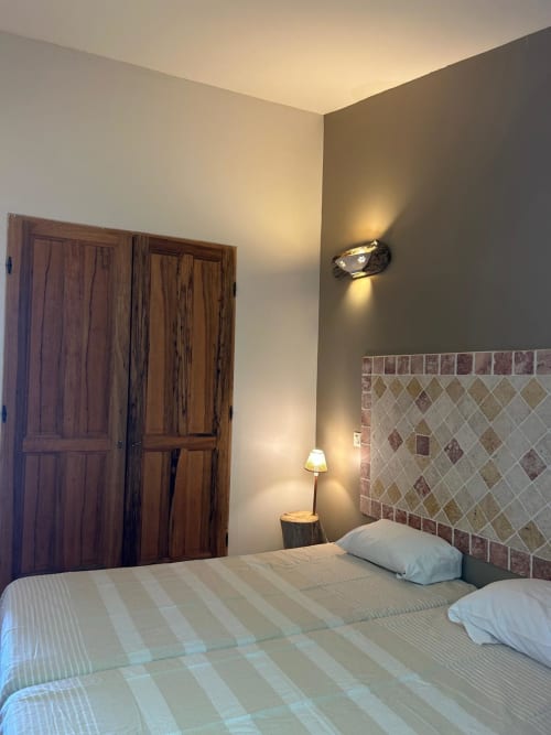 Chambre L'Alba à l'hôtel Vista D'oro à Monacia d'Aullène avec portes en bois, tête de lit carrelée et éclairage ambiant