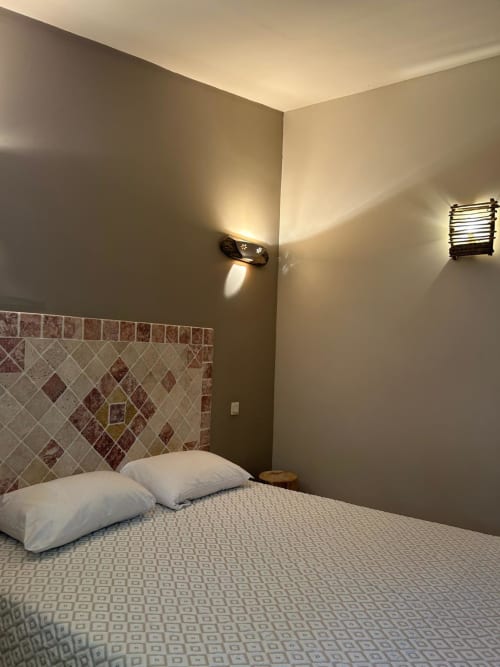 Chambre moderne à Vista D'oro, Monacia d'Aullène avec tête de lit carrelée, oreillers blancs et éclairage ambiant