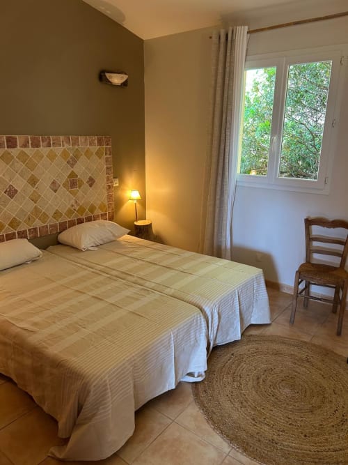 Chambre lumineuse à l'hôtel Vista D'oro à Monacia d'Aullène avec lits jumeaux, tête de lit en carrelage terracotta et vue sur mer