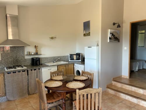 Cuisine entièrement équipée et salle à manger de la chambre L'Alba à Vista D'oro, Monacia d'Aullène avec table et chaises en bois
