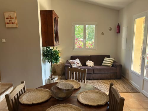 La chambre L'Alba à Vista D'oro en Corse : salon ouvert avec canapé marron, salle à manger, cuisine et vue sur la mer par les baies vitrées