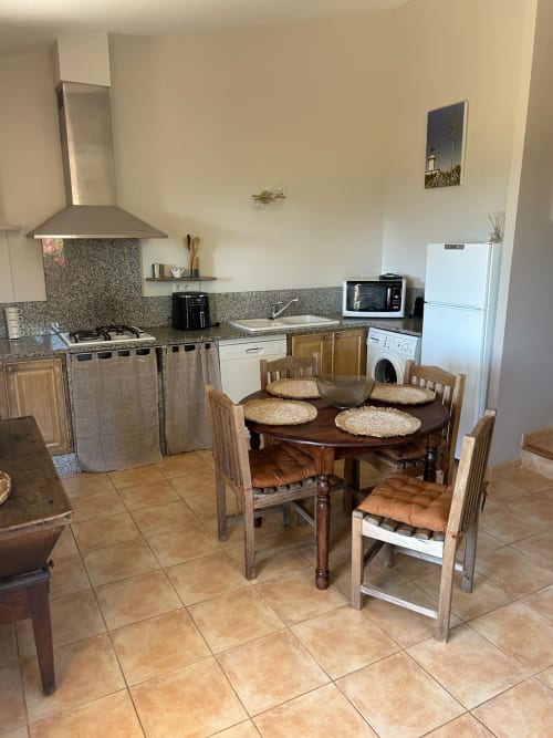 Cuisine entièrement équipée et salle à manger de la chambre L'Alba à Vista D'oro à Monacia d'Aullène avec appareils et table ronde en bois