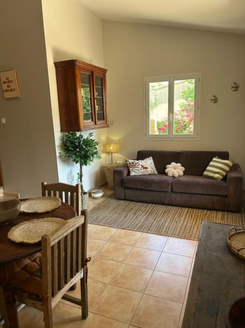 Séjour lumineux à Vista D'oro avec canapé sombre, chaises en bois, vue mer par portes vitrées et jardin à Monacia