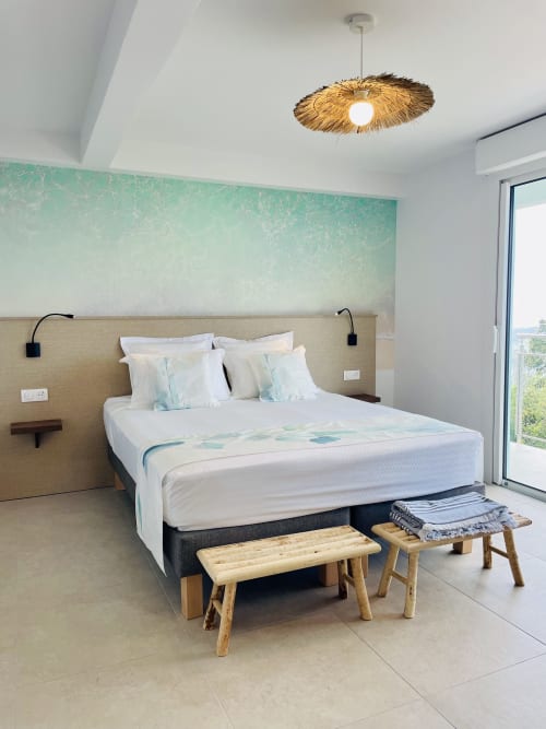 Chambre moderne avec literie blanche, mur d'accent turquoise, suspension en paille et vue sur mer à Villa Nid des Colibris