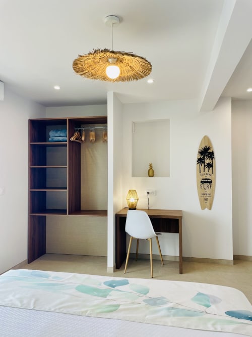 Chambre de villa moderne avec luminaire en suspension en paille, bureau de travail, décoration de planche de surf et accès à la vue mer aux Terrasses du Morne