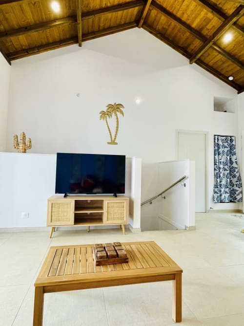 Salon moderne de villa avec mobilier en bois, téléviseur écran plat, décoration palmiers et plafond en bois massif aux Terrasses du Morne