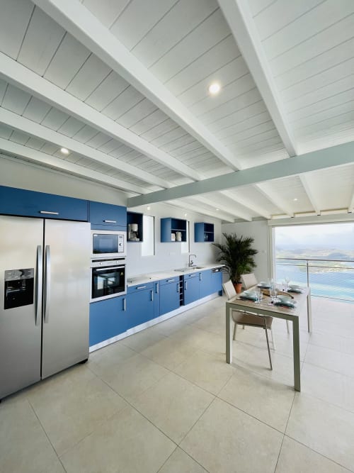 Cuisine moderne aux armoires bleues, plafond blanc à poutres, vue sur mer à Villa Nid des Colibris, Terrasses du Morne Gommier