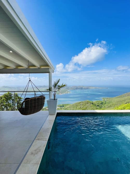 Villa avec piscine à débordement face à la baie turquoise de la Martinique, terrasse avec chaise suspendue et vue sur mer