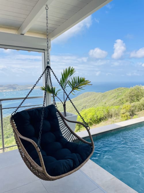 Fauteuil suspendu œuf avec coussin noir surplombant l'océan et les collines tropicales de la Villa Nid des Colibris, Martinique