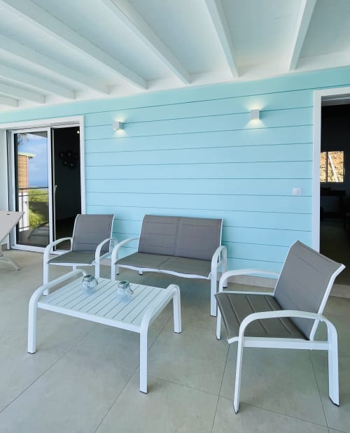 Patio couvert moderne à la Villa Nid des Colibris avec murs bleu clair, mobilier blanc et vue sur l'océan au Marin