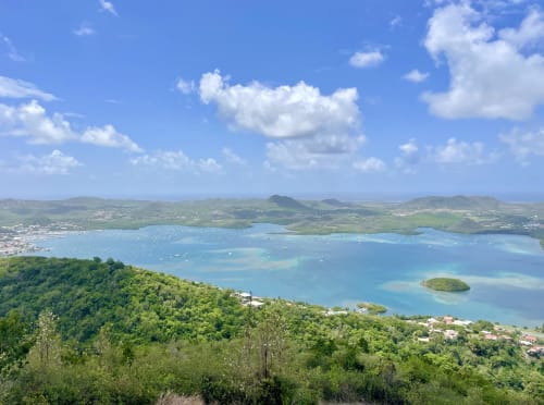 Baie turquoise avec voiliers, collines luxuriantes et vue sur le village côtier depuis la villa Terrasses du Morne Gommier au Marin