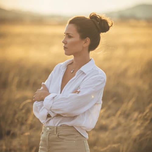 Mujer con camisa blanca de pie en campo de trigo dorado al atardecer cerca de Yecla