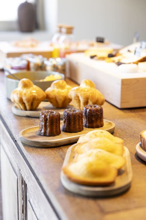 Présentation de pâtisseries artisanales à La Maison des Jardins, Gigondas. Canelés au chocolat et choux à la crème jaune sur des planches en bois