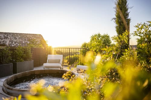 Terrasse luxueuse sur le toit de La Maison des Jardins à Gigondas avec bain à remous, chaise longue et vue sur le coucher de soleil