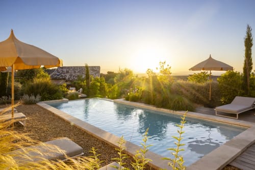 La piscine de La Maison des Jardins au coucher de soleil avec parasols et chaises longues, Gigondas