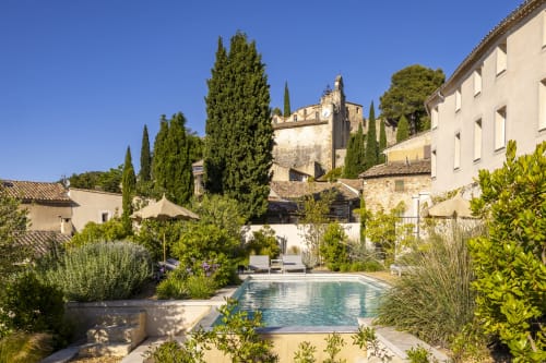 La cour intérieure de La Maison des Jardins avec piscine, cyprès et bâtisses en pierre à Gigondas