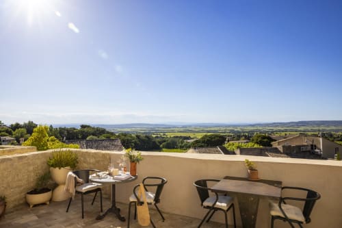 Terrasse ensoleillée de La Maison des Jardins à Gigondas avec tables de restaurant surplombant les vignobles et la campagne