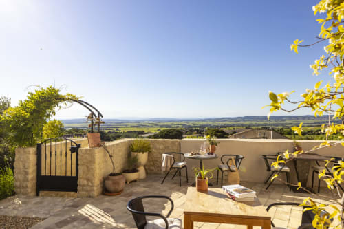 Terrasse ensoleillée de La Maison des Jardins à Gigondas avec vue panoramique sur la campagne, mobilier et fleurs jaunes