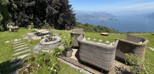 Luxus-Spa-Garten mit Blick auf den Lago Maggiore, Italien, mit Korbmöbeln und Feuerstelle