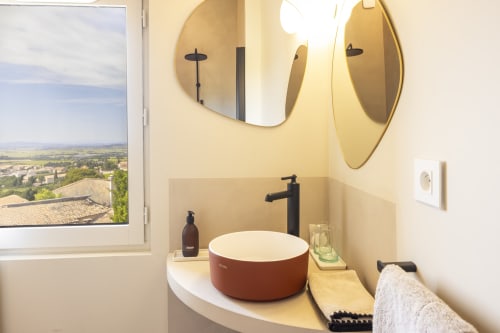 Salle de bain moderne à La Maison des Jardins à Gigondas avec vasque rouge, robinetterie noire et vue sur la campagne