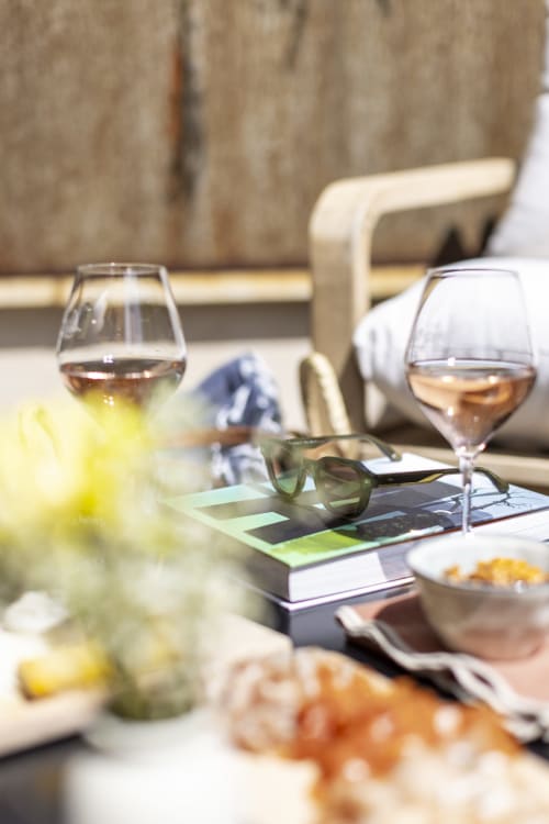 Élégante terrasse de jardin aménagée pour dîner à La Maison des Jardins avec verres de vin, lunettes de soleil et amuse-bouches