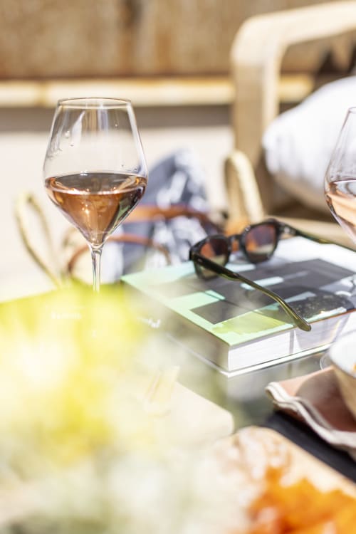 Verre de rosé sur la terrasse de La Maison des Jardins à Gigondas avec vue sur les jardins et lunettes de soleil