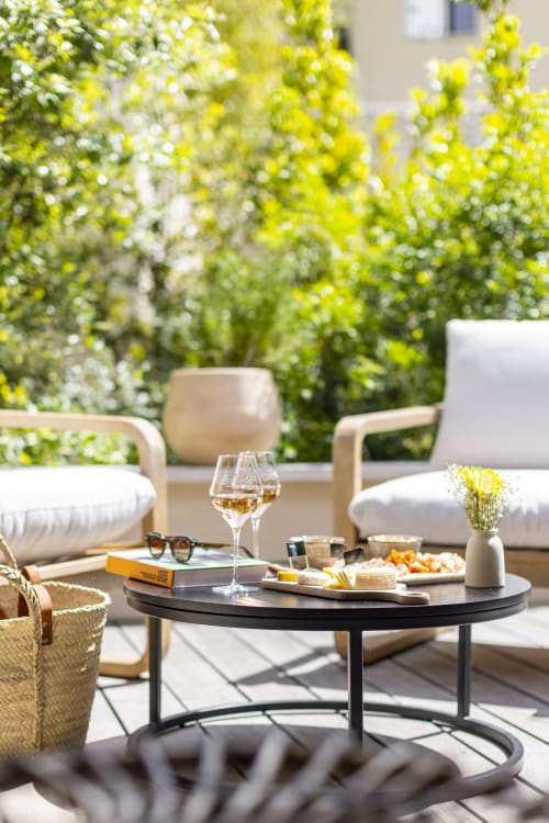Terrasse ensoleillée de La Maison des Jardins avec verres de vin, amuse-bouches et jardin aux fleurs jaunes à Gigondas