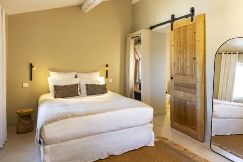 Chambre lumineuse à La Maison des Jardins avec lit queen-size, porte grange, miroir rond et vue sur le jardin à Gigondas
