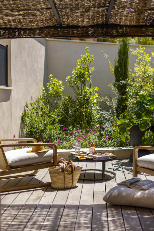 Terrasse ensoleillée du jardin à La Maison des Jardins à Gigondas avec chaises longues, table ronde et plantes luxuriantes avec fleurs