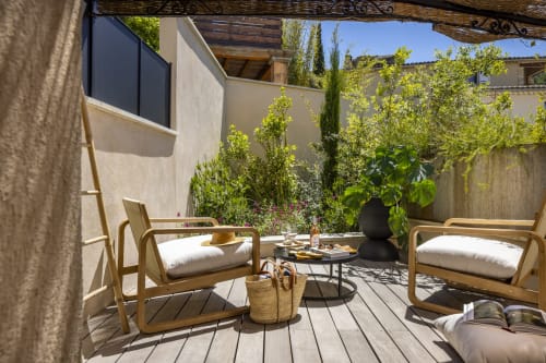Terrasse privée de La Maison des Jardins à Gigondas avec transats en bois, vue sur le jardin luxuriant et murs en pierre
