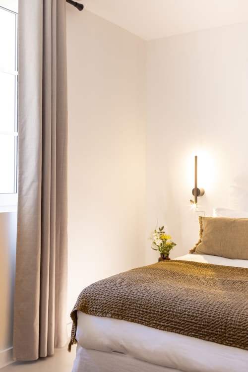 Chambre minimaliste à La Maison des Jardins B&B à Gigondas, avec un lit aux draps texturés, murs neutres et