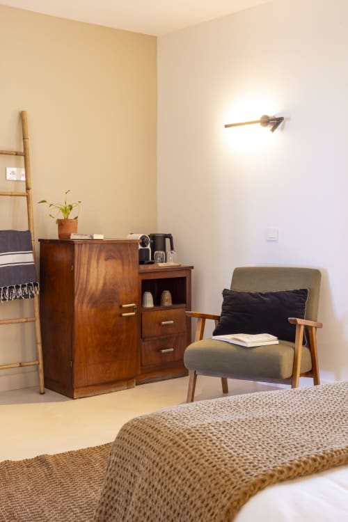 Chambre double cosy de La Maison des Jardins avec fauteuil vintage, meuble en bois et murs beige