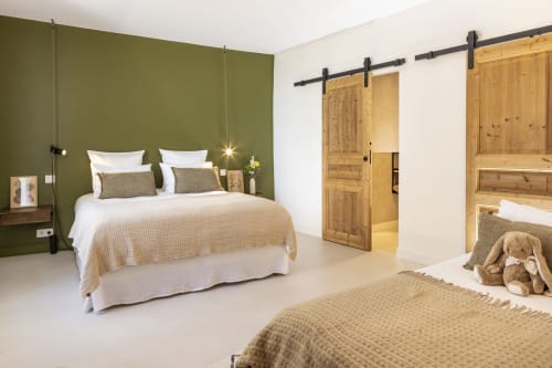 Chambre familiale de La Maison des Jardins, Gigondas avec mur d'accent vert olive, portes de grange en bois et design contemporain