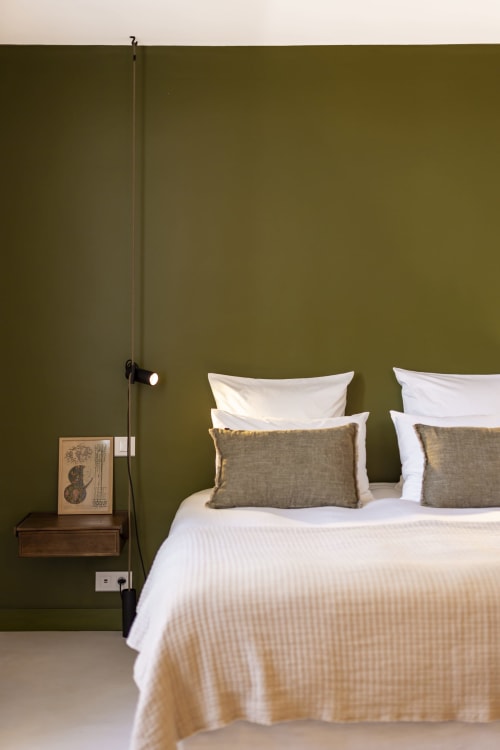 Chambre moderne à La Maison des Jardins à Gigondas avec murs couleur olive, literie blanche et luminaires suspendus