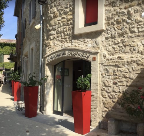 Entrée en pierre du Caveau du Gigondas avec jardinières rouges à La Maison des Jardins, chambre d'hôtes à Gigondas