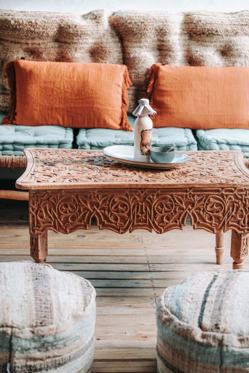 Table en bois sculpté avec coussins orange et plaid à motifs à la villa balnéaire Bleu Guesthouse à Saint-François