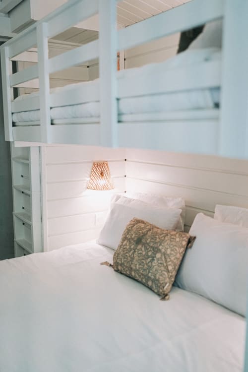 Chambre lumineuse avec lits superposés blancs, lampe tressée et coussin à motifs à la villa Bleu Guesthouse, Saint-François
