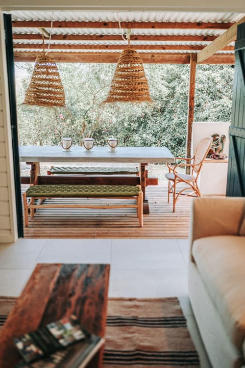 Terrasse de la villa Bleu Guesthouse avec luminaires suspendus tissés, mobilier en bois et vue sur les oliviers à Saint-François