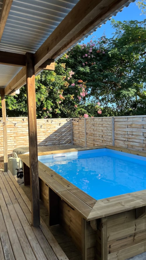 Terrasse en bois avec bain à remous couvert, revêtement bleu et vignes fleuries à la villa Bleu Guesthouse à Saint-Francois