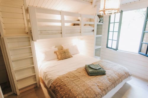 Chambre lumineuse de la villa côtière de Bleu Guesthouse avec lits superposés, échelle en bois et vue sur l'océan à Saint-François