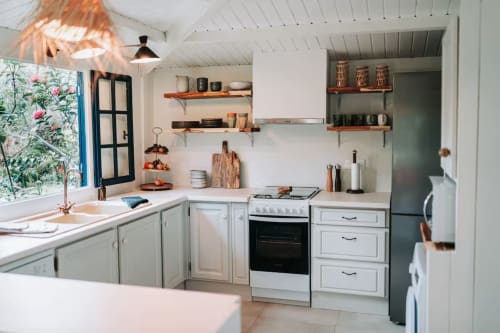 Cuisine moderne et lumineuse de la villa Bleu Guesthouse à Saint-François, avec meubles blancs, étagères ouvertes et vue sur le jardin en bord de mer