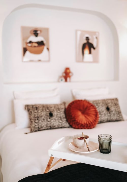 Chambre moderne au Bleu Guesthouse avec lit blanc, oreillers gris, fauteuil rouge et œuvre abstraite sur mur courbe