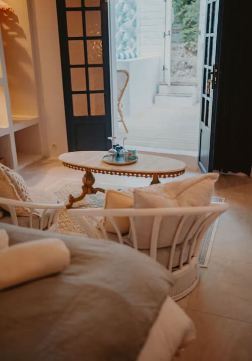 Élégant salon de la Suite Bleu Azur à Bleu Guesthouse avec canapé crème, table en bois et portes donnant sur la piscine